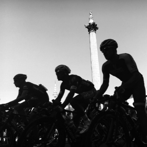 Cyklisté projíždění přes Trafalgarské náměstí pod Nelsonovým sloupem.